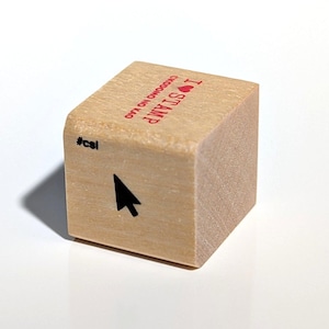May include: A light-colored wooden cube stamp featuring a black computer mouse cursor icon on the front face with the text #csl. The top face displays the red text I STAMP with a heart symbol and the red text OKODOMO NO KAO printed vertically.