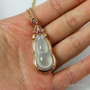 Puede incluir: Un colgante de jade en forma de calabaza, engastado en oro con diamantes y una piedra preciosa rosa. El colgante est&aacute; colgado de una cadena de oro.