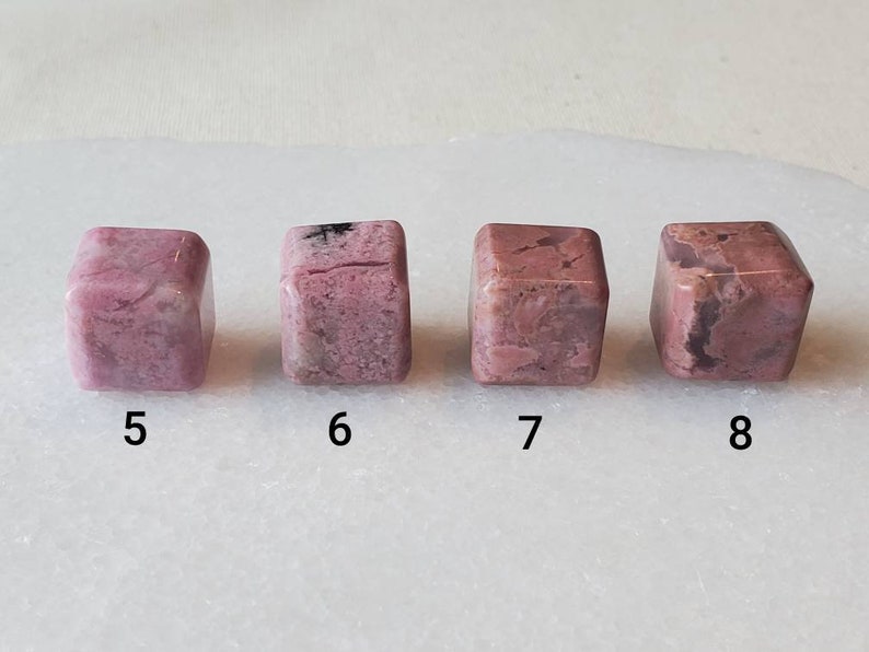 May include: Four pink and white, cube-shaped, polished stones with black veins. The stones are numbered 5 through 8.