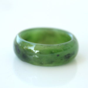 Könnte beinhalten: Ein grüner Jade-Ring mit schwarzen Flecken. Der Ring ist glatt und poliert.