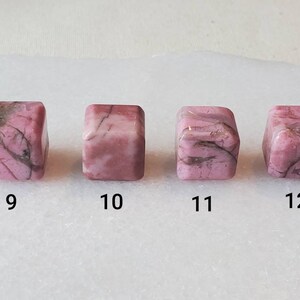 May include: Four pink and white, square-shaped, polished stones with black veins. The stones are numbered 9 through 12.
