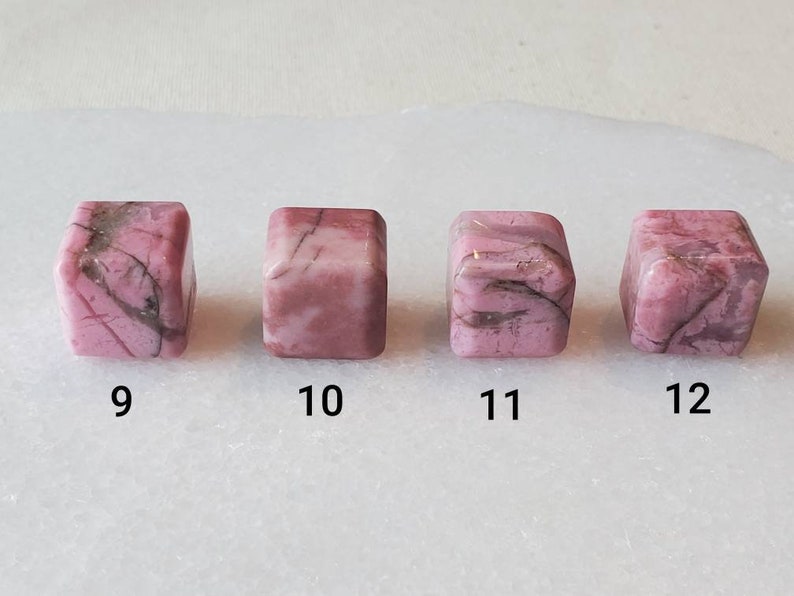 May include: Four pink and white, square-shaped, polished stones with black veins. The stones are numbered 9 through 12.