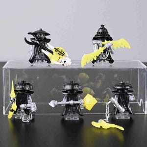 May include: A collection of black minifigures with various yellow accessories, including wings, scythes, and a mace. The figures are displayed on a clear acrylic stand against a neutral background. The figures have black hats and capes.