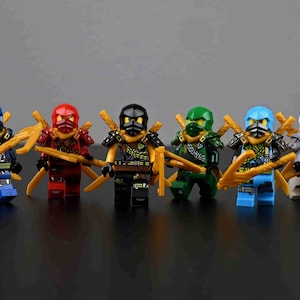 May include: Six colorful ninja action figures. Each figure is a different color: blue, red, black, green, light blue, and white. They are all wearing matching armor and holding golden weapons. The figures are standing in a row.