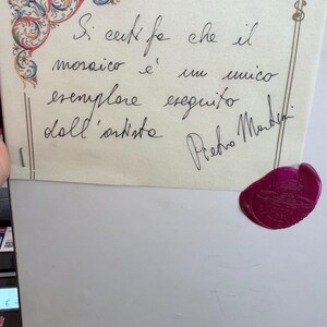 Pu&ograve; includere: Un certificato di autenticit&agrave; rettangolare con un decoro floreale nell'angolo in rosso, blu e verde. Presenta testo scritto a mano in italiano e una firma di Pietro Martini, rifinito con un sigillo in ceralacca magenta circolare nell'angolo.