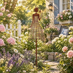 May include: A rust-colored metal garden stake featuring a stylized female figure with a wire-frame dress silhouette. The figure holds a single flower in one hand and is mounted on a thin vertical pole, designed for placement in a garden bed.