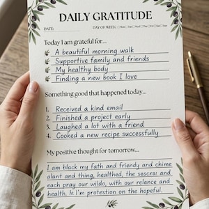 May include: A Daily Gratitude journal page with olive branch illustrations. The page includes prompts for daily reflections, such as things to be grateful for and positive thoughts for the future. The text includes "Today I am grateful for..." and "Something good that happened today..."