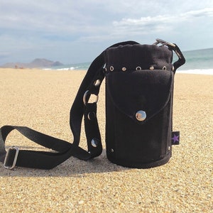 May include: Black canvas water bottle holder with a shoulder strap and silver accents. The holder has a small pocket on the front and a star-shaped logo.
