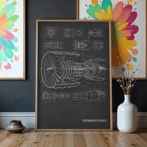 May include: A framed vertical print on a dark grey background featuring a white technical line drawing of a jet engine with various cross-section views and schematics. The text THEENGINEERSTUDIOCO. is printed in white in the bottom right corner.