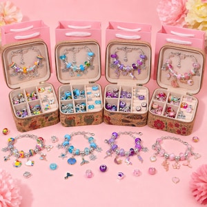 May include: Four square jewelry boxes with cork-textured bases and pink lids, each containing a charm bracelet and assorted beads. The bracelets feature colorful themes including rainbow, blue, purple, and pink, with various metal charms.