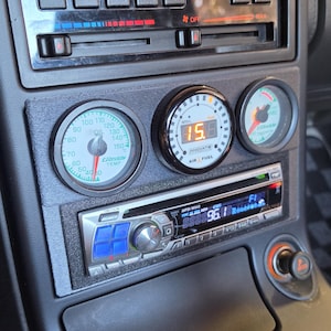 Może przedstawiać: Deska rozdzielcza samochodu ze wskaźnikami temperatury oleju i stosunku powietrza do paliwa. Wyświetlacz cyfrowy pokazuje "15.8", a radio wyświetla "96.1". Deska rozdzielcza posiada również elementy sterowania klimatyzacją i przycisk.