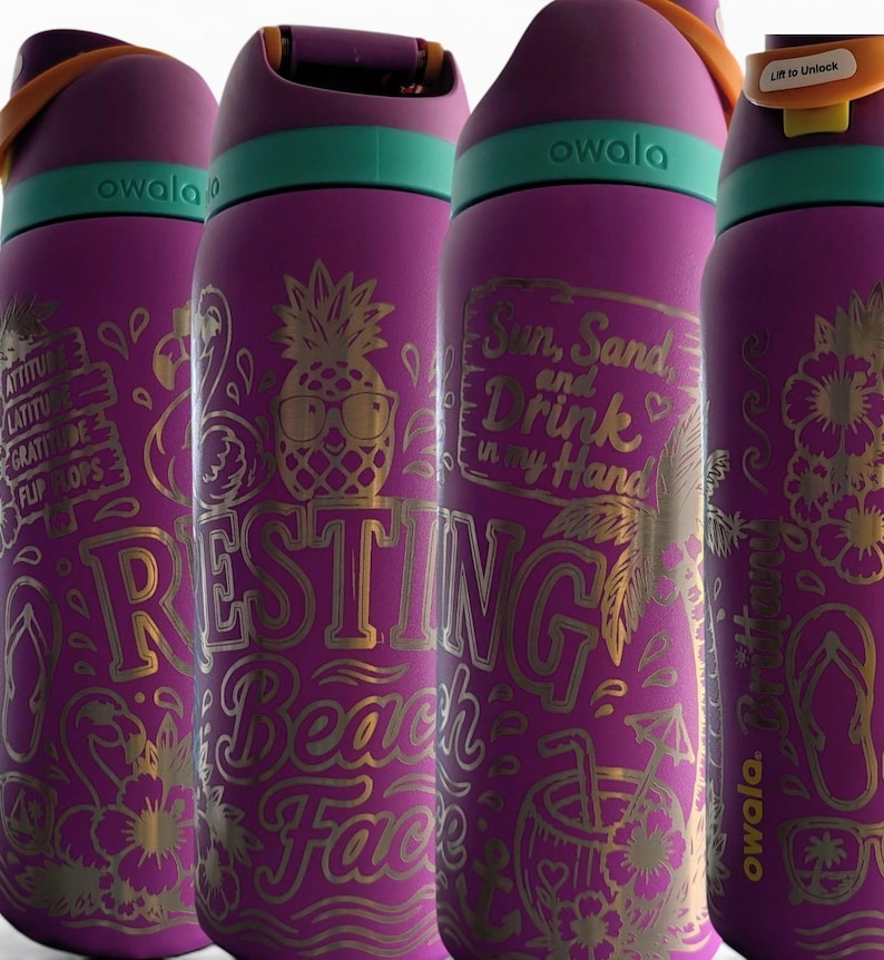 May include: Four purple Owala water bottles with teal accents and orange carry loops. Each bottle features gold-toned laser-engraved tropical designs, including pineapples, flamingos, and text such as Resting Beach Face and Sun, Sand, and Drink in my Hand.