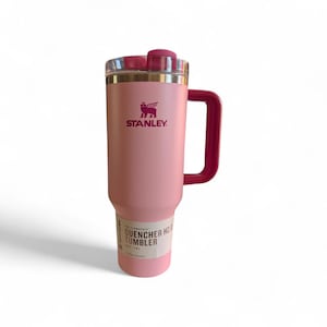 May include: A pink Stanley Quencher H2.0 Flowstate tumbler with a handle. The tumbler has a clear lid and a dark pink handle and accents. The Stanley logo is printed in dark pink. The tumbler has a capacity of 40 oz.