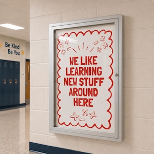 May include: A rectangular silver metal display case mounted on a wall, containing a white poster with a red scalloped border. The poster features the red text WE LIKE LEARNING NEW STUFF AROUND HERE, surrounded by various red mathematical symbols.