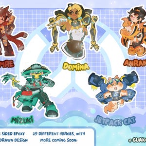 Puede incluir: Una colecci&oacute;n de cinco pegatinas de personajes ilustrados que incluyen a Emre, Domina, Anran, Mizuki y Jetpack Cat. El texto dice Double Sided Epoxy, 3 inch hand drawn design, 29 different heroes, with more coming soon y @guakocharms.