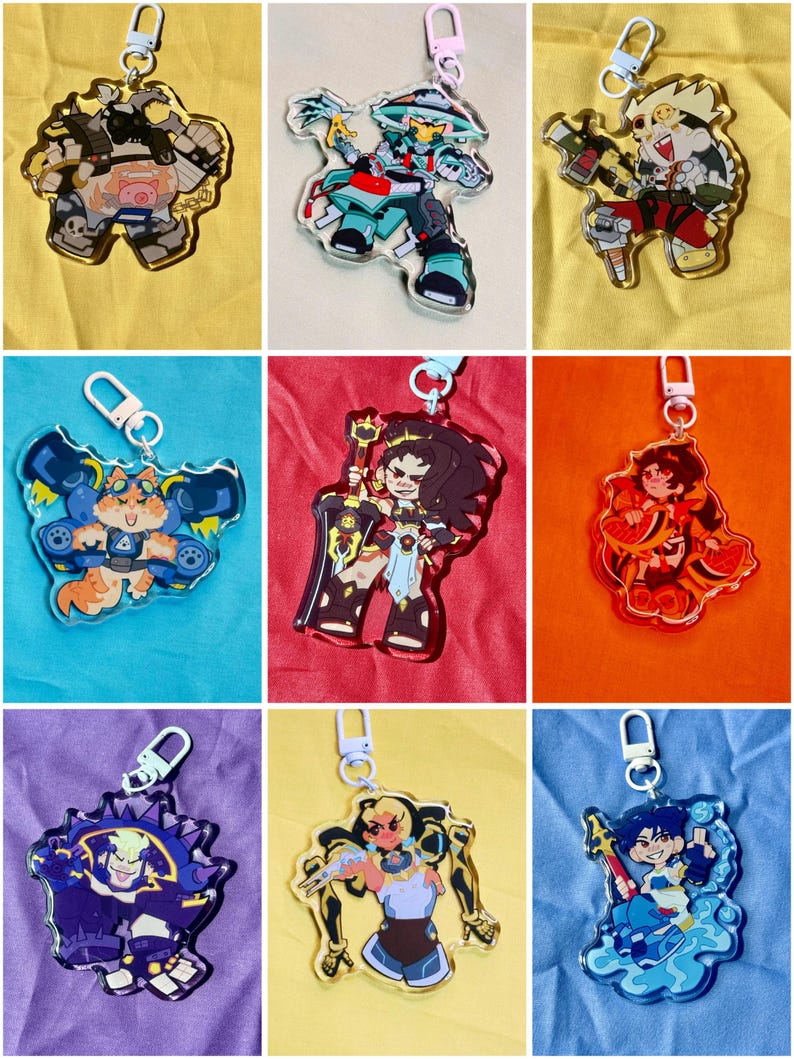Puede incluir: Una colecci&oacute;n de nueve llaveros de acr&iacute;lico con diversos personajes ilustrados en colores vibrantes, cada uno unido a un cierre de mosquet&oacute;n de pl&aacute;stico claro. Los dise&ntilde;os incluyen varias figuras en poses din&aacute;micas, mostrando l&iacute;neas detalladas y paletas audaces.