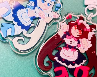 Könnte beinhalten: Zwei Schlüsselanhänger aus Acryl mit Illustrationen von Anime-Charakteren in Maid-Outfits. Einer ist weiß und blau, der andere rot, rosa und schwarz. Jeder Schlüsselanhänger hat einen transparenten Rand und einen weißen Verschluss.