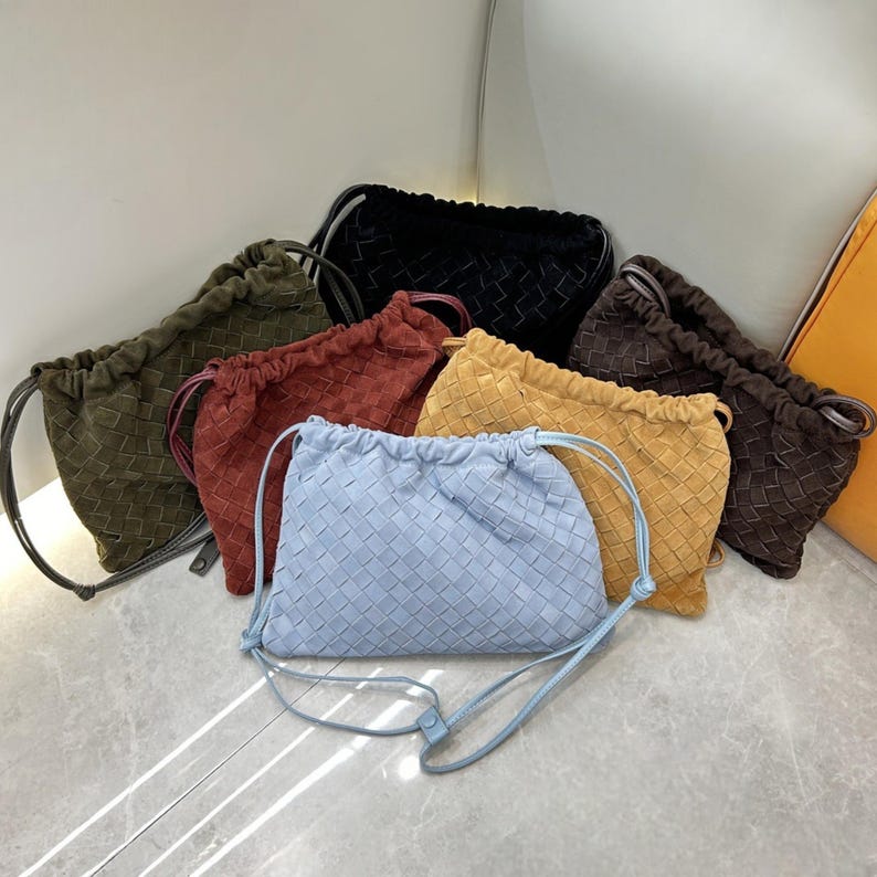 Puede incluir: Una colecci&oacute;n de bolsos con cord&oacute;n tejido en varios colores, incluyendo azul claro, negro, marr&oacute;n, amarillo, rojo y verde oliva. Cada bolso presenta un patr&oacute;n tejido y un cierre de cord&oacute;n. Los bolsos se exhiben sobre una superficie clara.