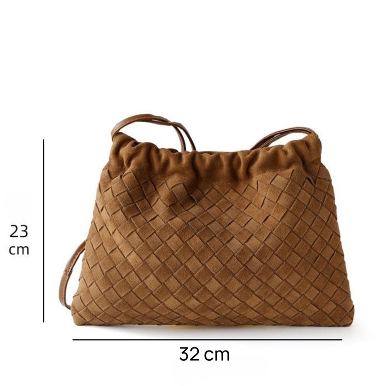 Puede incluir: Un bolso marr&oacute;n tejido con cierre de cord&oacute;n. El bolso mide 23 cm de alto y 32 cm de ancho. Tiene un patr&oacute;n tejido y una correa para el hombro.