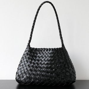 May include: Black woven leather shoulder bag with a braided handle. The bag has a trapezoid shape and a woven pattern throughout the body. The handle is also braided and appears sturdy. The bag is set against a white background.