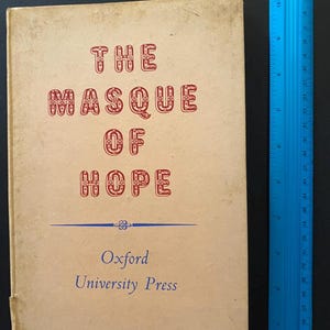 Op de afbeelding: Een vintage boek getiteld "The Masque of Hope" met rode letters op een crèmekleurige omslag. Het boek is van Oxford University Press. Een blauwe liniaal is naast het boek geplaatst.