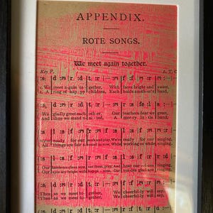Puede incluir: Partitura vintage enmarcada con texto rojo sobre papel envejecido. El texto dice "APPENDIX. ROTE SONGS. We meet again together." El marco es negro. La partitura es una pieza de arte mural única.