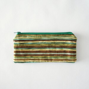 Puede incluir: Una bolsa de cremallera verde con un patr&oacute;n de rayas en tonos marrones, verdes y azules.