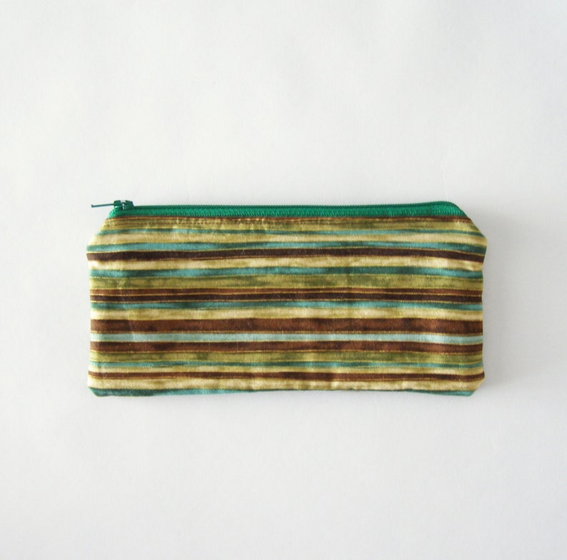 Puede incluir: Una bolsa de cremallera verde con un patr&oacute;n de rayas en tonos marrones, verdes y azules.