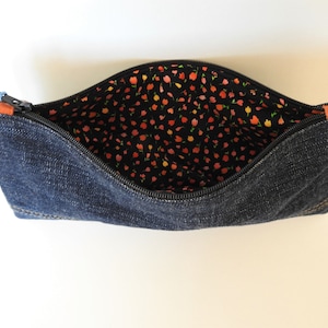 May include: A denim zippered pouch with a black and orange floral lining. The pouch is open and the zipper is visible.