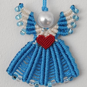 以下が含まれることがあります： 赤色のハートと真珠のビーズが付いた青と白の天使のオーナメント。天使は紐とビーズで作られています。