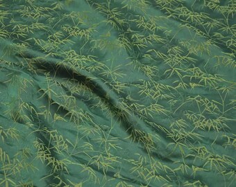 May include: A dark green fabric featuring a repeating pattern of light green bamboo leaves and stalks. The material has a soft, slightly wrinkled texture with folds that create natural shadows across the surface of the textile.