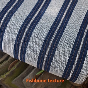 May include: White and blue striped fabric with a herringbone texture. The fabric has a subtle brown stripe running through it.