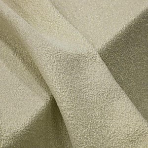 Puede incluir: Primer plano de una tela brillante y texturizada en color oro claro. El material está doblado, revelando el intrincado tejido y las sutiles variaciones de tono. La tela tiene un aspecto ligeramente áspero, pero elegante.