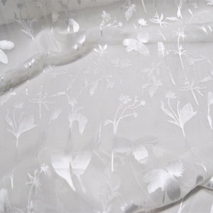 May include: White sheer fabric with an embossed floral pattern. The fabric is translucent and has a subtle sheen.