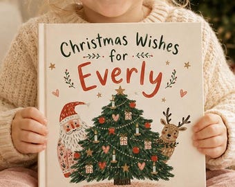 Puede incluir: Un libro cuadrado de tapa dura con una cubierta de color crema que presenta el texto Christmas Wishes for Everly en negro y rojo. La ilustración muestra un árbol de Navidad verde decorado, un Santa Claus sonriente y un reno, con pequeños corazones.