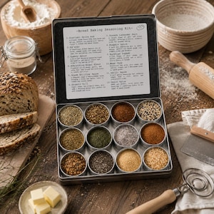 Peut inclure: Une boîte en métal contenant douze récipients circulaires remplis de diverses épices et assaisonnements, étiquetée comme un kit d'assaisonnement pour la cuisson du pain. Le couvercle présente une liste imprimée de douze mélanges d'épices, notamment Souvlaki Spice Rub, Za'atar, Speedy Spice, Everything Bagel Blend, Greek Grilling Spice, Organic Dill, French Lavender Salt, Pumpkin Spice, Egyptian Dukkah, Mama Chia, Garlic Sense et Onion Spice.