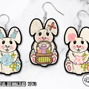May include: Three Easter bunny earrings with black outlines and silver hooks. Each bunny has a unique design, including flowers, butterflies, and a basket with eggs. The bunnies are cream-colored with pink cheeks and paws. The text "DIGITAL DOWNLOAD 2026" is at the bottom.