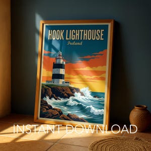 May include: A framed poster print featuring a graphic illustration of Hook Lighthouse in Ireland. The artwork displays a black and white striped lighthouse on a rocky cliff above crashing blue waves under a sunset sky with orange clouds.