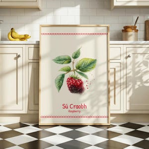 Può includere: Una stampa artistica da parete rettangolare verticale con un'illustrazione botanica dettagliata di un singolo lampone rosso con foglie verdi. Il testo Sú Craobh e Raspberry è stampato in rosso sotto il frutto, incorniciato da bordi smerlati.