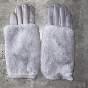 May include: A pair of light grey gloves featuring a smooth, matte finish on the fingers and a plush, textured faux fur cuff covering the back of the hand. The gloves are uniform in colour and design, showcasing a soft, tactile appearance.