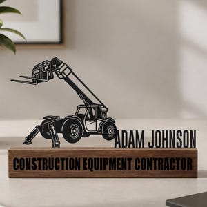 May include: A black metal cutout of a telehandler construction vehicle positioned next to the name ADAM JOHNSON in black lettering, all mounted on a rectangular wooden base with the text CONSTRUCTION EQUIPMENT CONTRACTOR printed on the front.
