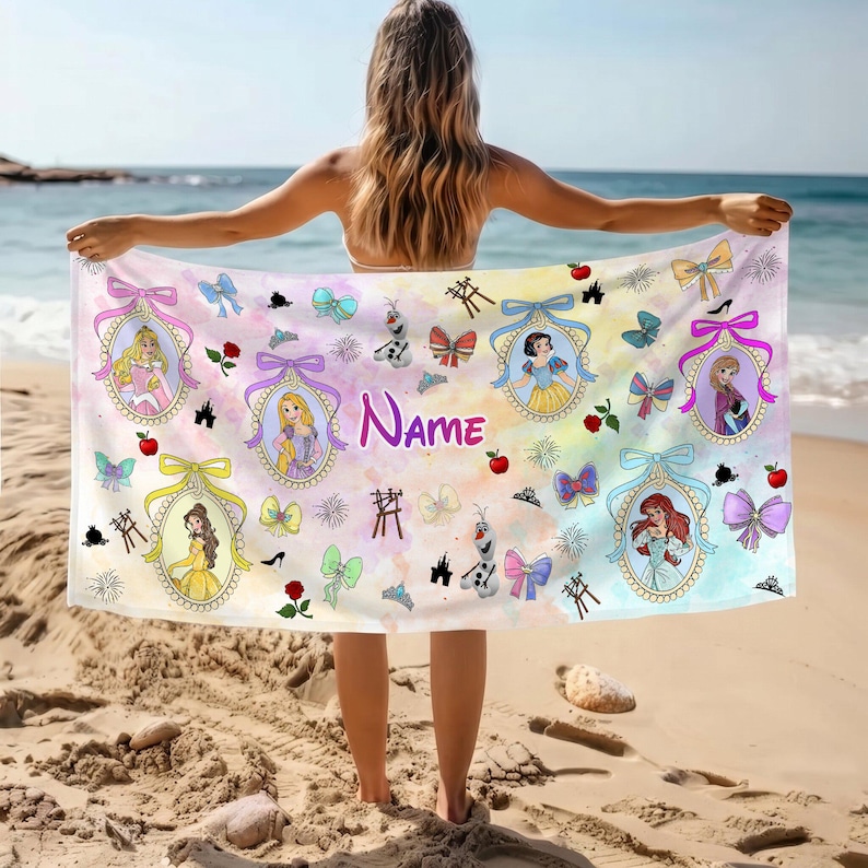May include: A rectangular beach towel featuring a watercolor-style background in pastel shades. The towel displays multiple illustrated Disney princesses inside ornate oval frames, interspersed with bows, roses, castles, and the word Name.