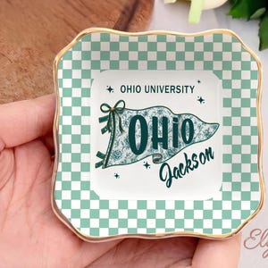 May include: Square ceramic trinket dish with a gold rim and a green and white checkered border. The centre features a pennant design with the text "OHIO UNIVERSITY" and "OHIO Jackson" in teal.