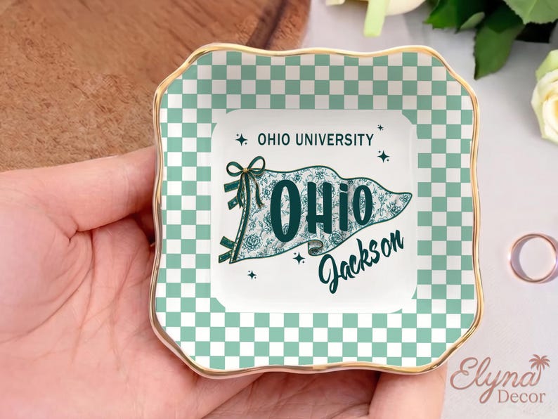 May include: Square ceramic trinket dish with a gold rim and a green and white checkered border. The centre features a pennant design with the text "OHIO UNIVERSITY" and "OHIO Jackson" in teal.