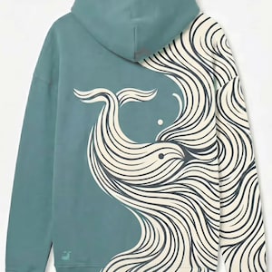 May include: Teal hoodie featuring a whale design. The back of the hoodie showcases a stylized whale illustration in cream and black, with flowing lines. The hoodie has a hood and long sleeves, and a small logo is visible on the lower left.
