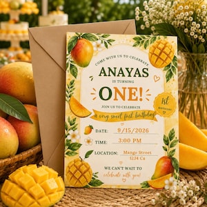 May include: A rectangular birthday invitation card featuring mango illustrations, green leaves, and white flowers. The text reads: COME WITH US TO CELEBRATE ANAYAS IS TURNING ONE! JOIN US TO CELEBRATE a very sweet first birthday! DATE: 9/15/2026 TIME: 3:00 PM LOCATION: Mango Street 1234 Ca WE CAN'T WAIT TO celebrate with you!