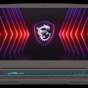 Może przedstawiać: Szary laptop z podświetlaną klawiaturą i ekranem z logo smoka w tarczy. Ekran posiada r&oacute;wnież czerwone i fioletowe linie neonowe. Laptop znajduje się na czarnym tle.