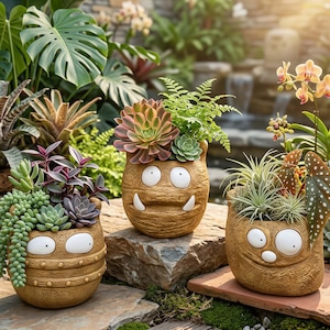 May include: Three whimsical, brown ceramic planters with cartoon monster faces, each filled with a variety of succulents and greenery. The planters have textured surfaces and are arranged outdoors on a stone surface, with a waterfall in the background.