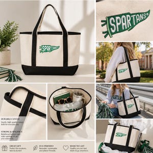 May include: Cream-colored canvas tote bag with black accents and the word "SPARTANS" on a green pennant. The bag has sturdy handles and a reinforced bottom. The bag is shown with various items inside, including sunglasses and a tumbler.