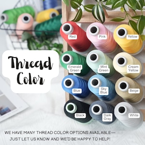 May include: A display of colorful thread spools in various shades, including red, pink, yellow, and green. The image features a wooden rack with labeled thread colors, such as "Blue," "Black," and "White." The text "Thread Color" is also visible.